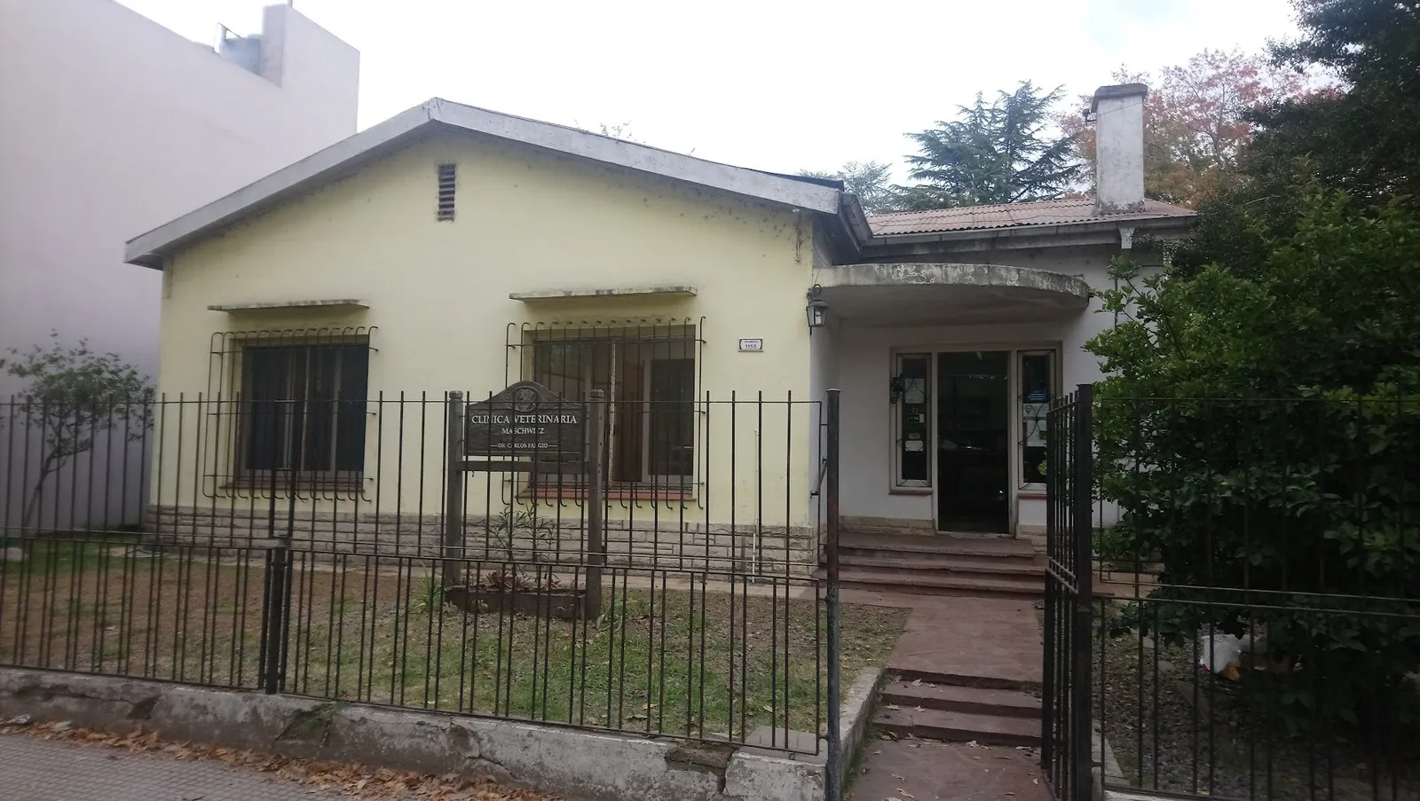 La casa de la veterinaria, con su jardín, la reja negra y el cartel de madera